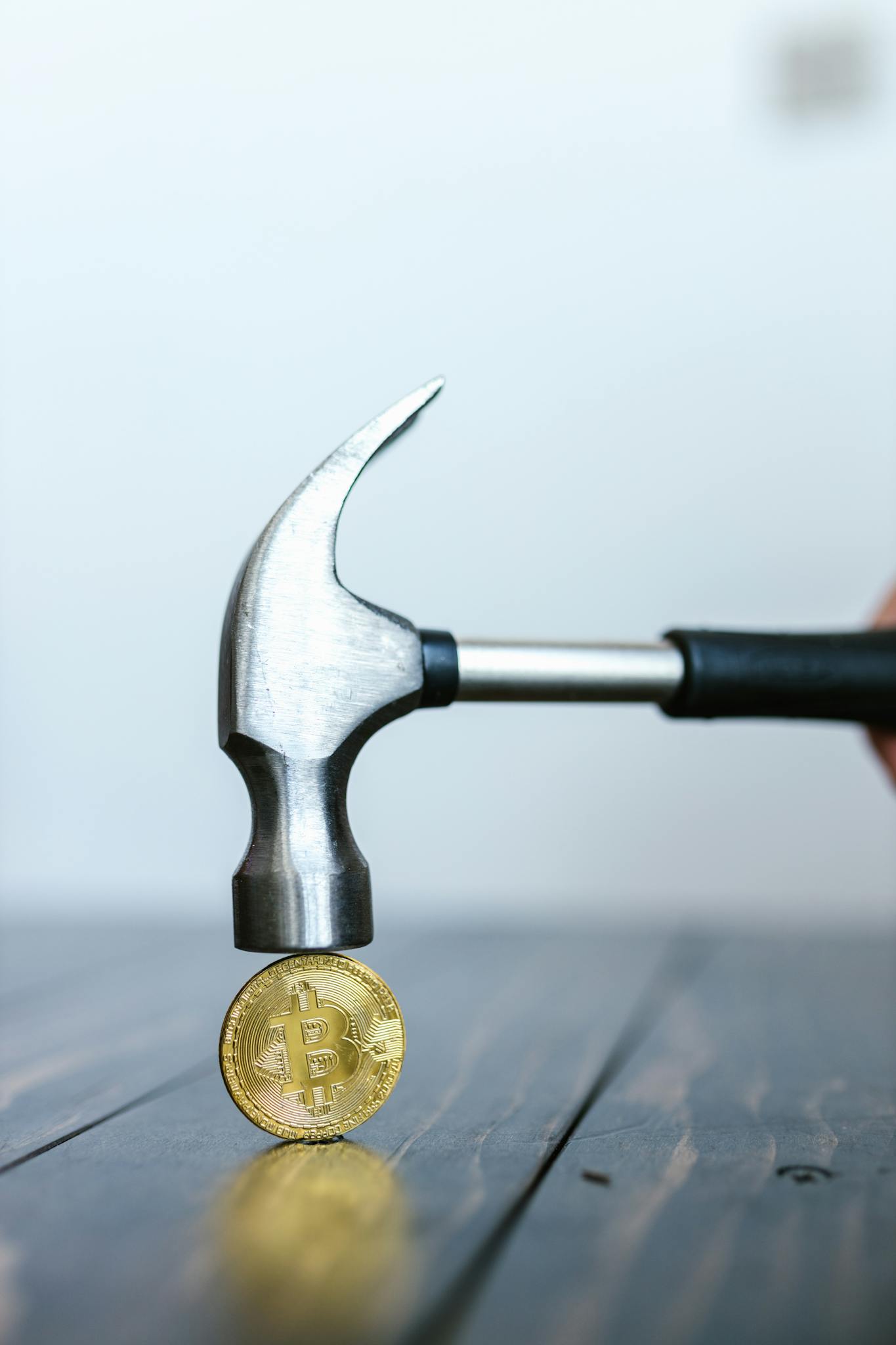 Person Knocking a Golden Bitcoin Token with a Hammer